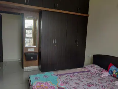 a bedroom with a bed and wooden cabinets at Suvarna Compact in Mysore
