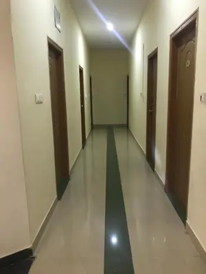 a hallway of a building with two doors and a long corridor at Suvarna Compact in Mysore