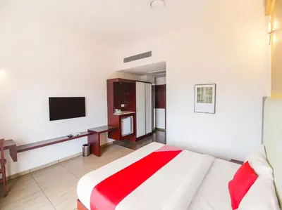 a hotel room with a bed and a tv at Samudra Mysore in Mysore