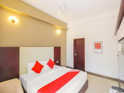 a hotel room with a bed with red pillows at Samudra Mysore in Mysore