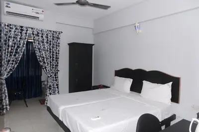 a bedroom with a white bed with a black headboard at Hotel Span in Kozhikode