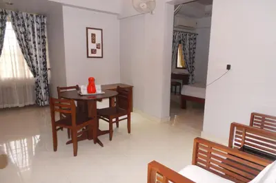 a living room with a table and chairs and a bedroom at Hotel Span in Kozhikode