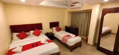 a hotel room with two beds and a mirror at Hotel Green Plaza in Trichūr