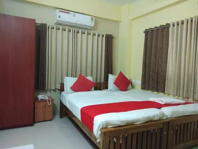 a bedroom with a large bed with red pillows at Hotel Green Plaza in Trichūr