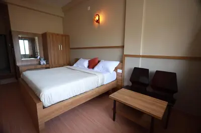 a small bedroom with a bed and a chair at Haksons Residency in Mananthavady