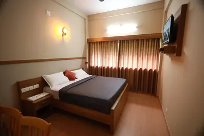 a small room with a bed and a television at Haksons Residency in Mananthavady