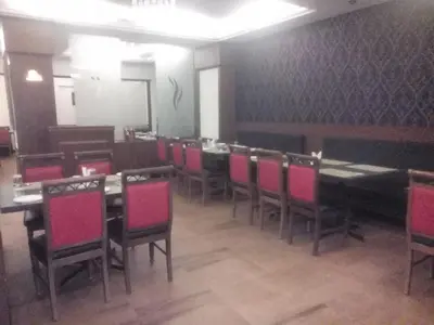 a dining room with tables and chairs with pink chairs at President Hotel in Mysore