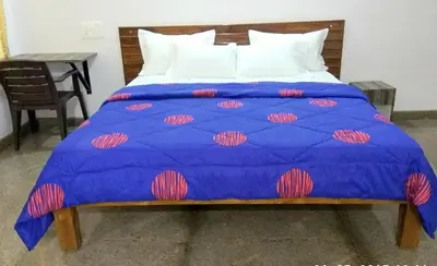 a blue bed with a blue comforter and white pillows at Aashraya Homestay in Mysore