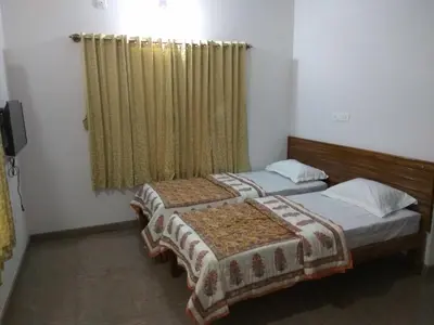 two beds in a room with a window at Aashraya Homestay in Mysore