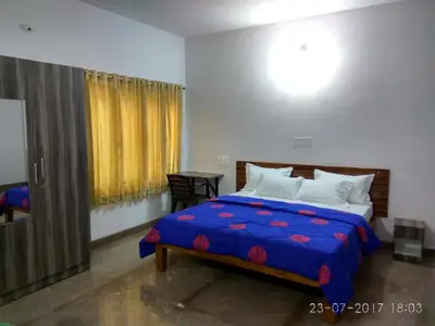 a bedroom with a bed with a blue comforter at Aashraya Homestay in Mysore