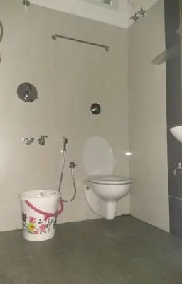 a bathroom with a toilet and a bucket at Aashraya Homestay in Mysore