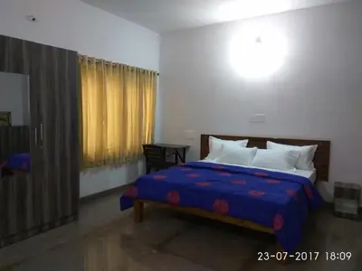 a bedroom with a bed with a blue comforter at Aashraya Homestay in Mysore