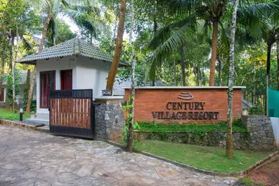 a sign in front of a building with trees at Century Village Resort in Mananthavady
