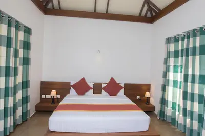 a bedroom with a bed and two lamps and curtains at Century Village Resort in Mananthavady
