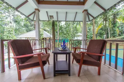 two chairs and a table on a screened in porch at Century Village Resort in Mananthavady