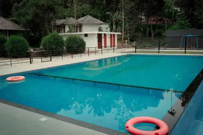 a blue swimming pool with a red float in front of a house at Century Village Resort in Mananthavady