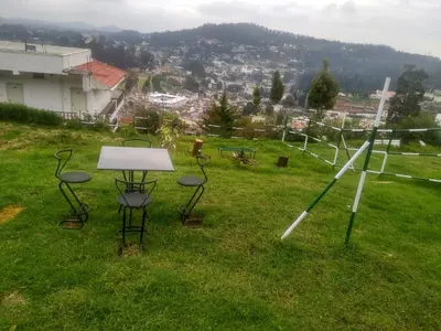 a group of chairs and a table on a field at Berry Hills Resort in Ooty