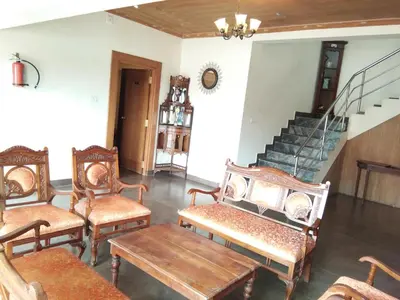 a room with chairs and a table and stairs at Berry Hills Resort in Ooty