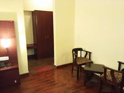 a living room with a table and a chair and a room with a door at Berry Hills Resort in Ooty