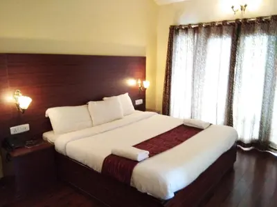 a hotel room with a large bed with white sheets at Berry Hills Resort in Ooty