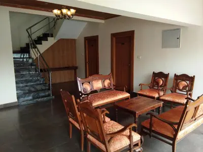 a room with chairs and a table and a staircase at Berry Hills Resort in Ooty