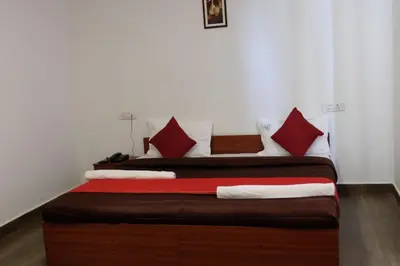 a bedroom with two beds with red and white pillows at Rosepark Residency in Ooty