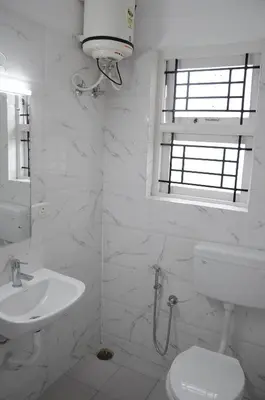 a white bathroom with a sink and a toilet at Rosepark Residency in Ooty