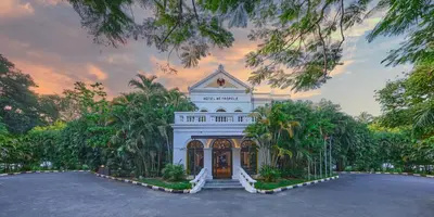 a large white building with trees in front of it at Royal Orchid Metropole Mysore in Mysore