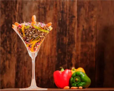 a drink in a martini glass next to some vegetables at Teanest Nightingale by Nature Resorts and Stays in Kotagiri