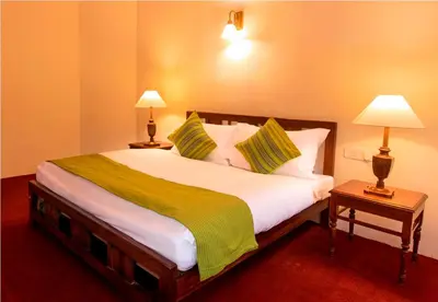 a bedroom with a large white bed with two lamps at Teanest Nightingale by Nature Resorts and Stays in Kotagiri