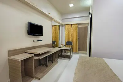a room with a desk and a tv on the wall at Mannars Deluxe Lodge in Mysore