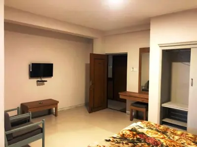 a hotel room with a bed and a tv on the wall at Hotel Preethi Palace in Ooty