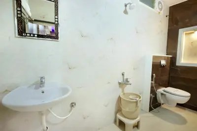 a bathroom with a sink and a toilet and a mirror at Mannars Yatri Nivas Hotel in Mysore