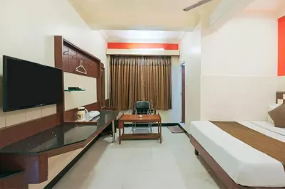 a hotel room with a bed and a desk with a television at Mannars Yatri Nivas Hotel in Mysore