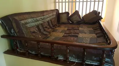 a wooden bed with pillows on top of it at Wayanad Homestay in Kalpetta