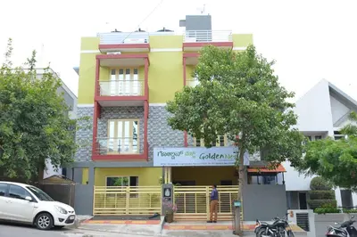 a yellow building with a sign in front of it at Golden Nest in Mysore