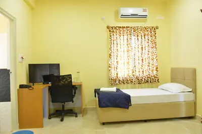 a room with a bed and a desk with a computer at Golden Nest in Mysore