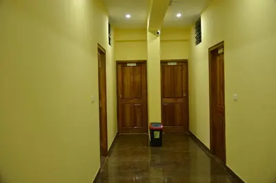 a hallway with three doors and a trash can at Golden Nest in Mysore