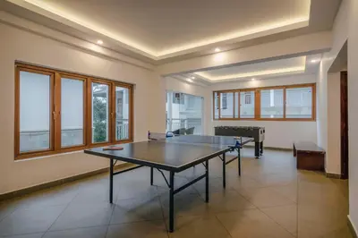 a ping pong table in a room with windows at Elixir Hills Suites Resort and Spa in Munnar