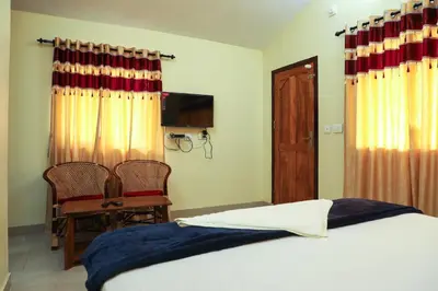 a bedroom with a bed and two chairs and a television at Green Garden Deluxe Room in Vayittiri