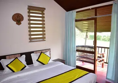 a bedroom with a bed with yellow pillows and a balcony at KOOMANKOLLY RESORT in Thirunelli