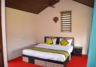 a bedroom with a bed with yellow pillows and a window at KOOMANKOLLY RESORT in Thirunelli