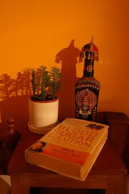 a book on a table with a lamp and a plant at Namasthe Ayurveda and Yoga Retreat Cochin Only for Ayurveda and Yoga Wellness Stay in Nedumbassery