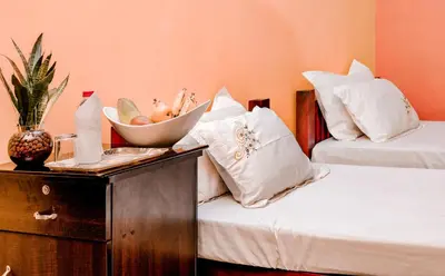 a bedroom with two beds and a bowl of fruit on a table at Namasthe Ayurveda and Yoga Retreat Cochin Only for Ayurveda and Yoga Wellness Stay in Nedumbassery