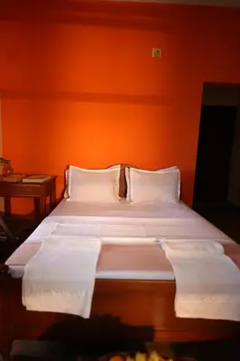 a bed in a room with an orange wall at Namasthe Ayurveda and Yoga Retreat Cochin Only for Ayurveda and Yoga Wellness Stay in Nedumbassery