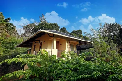 a small yellow house in the middle of a forest at Vista Del Lago in Ambalavayal