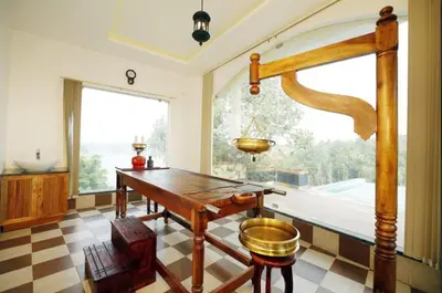 a dining room with a table and a large window at Vista Del Lago in Ambalavayal