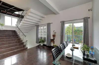a living room with a glass table and a staircase at Kurinji Wanderlust Resort Munnar in Munnar