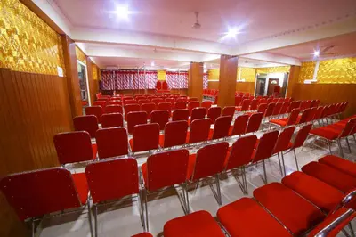 an empty auditorium with red chairs in a building at Avanti Inn in Guruvāyūr
