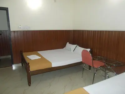 a bed and a chair in a room at Avanti Inn in Guruvāyūr